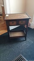 Front view of wicker ratan side table with two drawers and woven ratan tabletop surface.