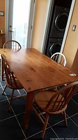 Wooden rectangular dining table with four matching chairs in kitchen space.