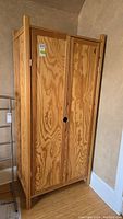 Front view of the Ikea Bialett pine wardrobe showing both doors closed and wood grain pattern with visible wear.