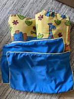 Curtain panels and matching pillow covers showing front and back of pillow covers in blue and animal print pattern