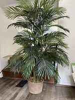 Full view of tall artificial palm tree showing lush green fronds and textured pot base.