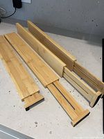 Photo of three bamboo adjustable drawer dividers arranged on a surface showing the full length and typical construction