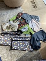 Overview of all diaper bags and changing mats arranged on the floor, showing multiple colors and patterns including polka dots, floral, and solid.