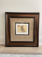 Framed Disney Tinkerbell storyboard sketch reproduction shown upright with brown frame and beige matting, paper sketch centered.