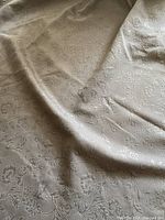 Close-up of gray curtain panel showing floral texture and fabric condition