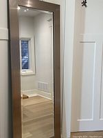 Full view of large rectangular mirror leaning against wall and door showing size and frame style.