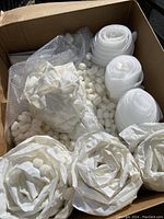 Viewing a large open cardboard box filled with rolled white packing paper, foam wrap rolls, and packing peanuts inside.