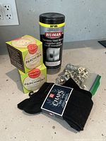 Photo showing all items together: stainless steel wipes container, parchment liner boxes, black socks, and cabinet brackets in a bag.