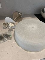 Photo showing the frosted white glass shade with crosshatch design, along with the metal mounting base and light bulb socket assembly placed on a countertop.