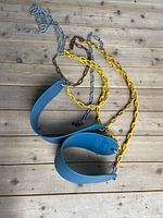Two green flexible swing seats with attached metal chains—yellow and silver chains visible, seats slightly curved to support seating.