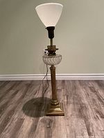 Full view of the antique brass table lamp showing height, square base, and white conical shade.