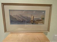 Framed landscape painting with sailboats and mountains, in beige frame with matting