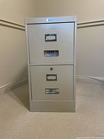 Front angled view of the light gray 2-drawer filing cabinet showing metal handles and label holders.