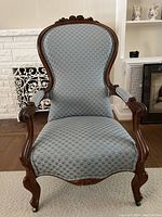Front view of the antique gentlemen's chair showing blue patterned upholstery and carved wooden frame.