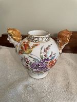 Front view showing overall shape, floral decoration, and female bust handles