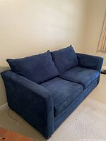 Blue pullout couch with two large seat cushions and two large back cushions, upholstered in a blue velvety fabric.