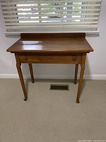 Front view of small wooden desk showing single drawer and tapered legs