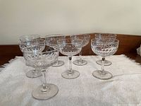 Eight vintage crystal champagne glasses arranged on a white towel, showing the full set.