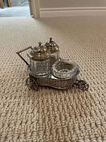 Miniature sterling silver wheeled cart holding two clear glass shakers with silver lids and one scalloped glass bowl