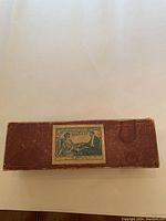 Closed red textured box with vintage game label on top