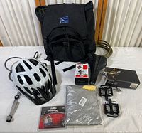 Full lot overview showing helmet, backpack, Shimano pedals in box, bicycle seat, bike lock, bike light, bike cover, phone holder.