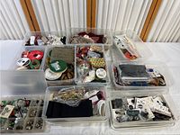 Overview of multiple plastic containers filled with various crafting and sewing supplies including ribbons, fabrics, and hardware