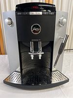 Front view showing dual coffee spouts, control panel with LED display and steam wand at right