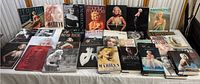 Full view of 22 Marilyn Monroe hardcover books lined up on a table, showing covers with various portraits and themes related to Marilyn Monroe.