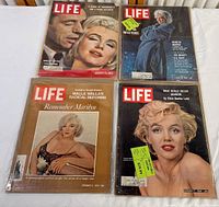 Four LIFE magazines with Marilyn Monroe on covers placed on a white surface, showing front covers and general condition.