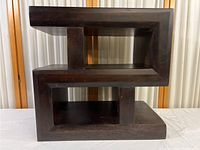 Front view of the dark wood side table showing geometric rectangular design and open shelves.