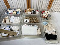 Overview showing nine clear plastic containers filled with assorted ribbon spools and fabric trims in various colors and styles.