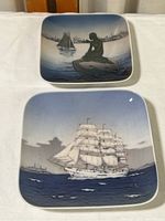 Both square trinket dishes shown on white cloth background, one with a sailing ship and one with a mermaid.