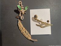 Three vintage brooches displayed on black and white backgrounds showing insect, leaf and musical note designs