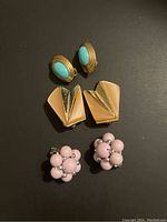 Three pairs of vintage clip-on earrings on black background showing front design and condition.