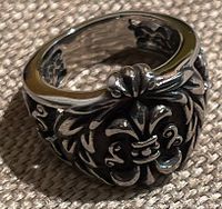 Close-up photo of silver tone thick gothic ring showing top and side detailing.