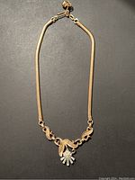 Full view of Trifari gold tone choker necklace with rhinestone flower pendant.