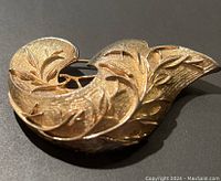Close-up front view showing the textured leaf design in gold-tone metal.