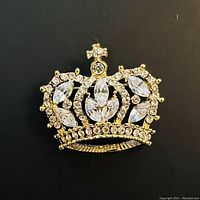 Close-up image of the vintage rhinestone gold plated crown-shaped brooch with crucifix cross detail.