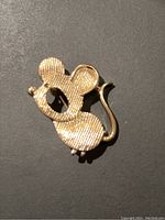 Front view of the gold tone mouse brooch showing textured metal surface and pin design.