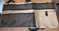Front view of organizer showing multiple mesh pockets and fabric compartments with beige trim and black mesh.