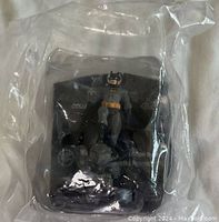 Sealed Batman figurine in original plastic packaging, showing front view with visible details of the figure and Heroclix branding.