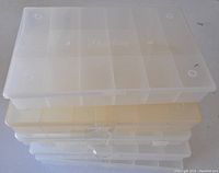 Stacked nine translucent plastic storage trays with multiple rectangular compartments and lids.