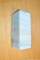Polished Caribbean Blue Calcite standing point tower showing smooth polished blue and white banded surfaces with pointed top and flat base.