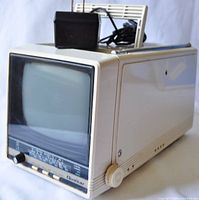 Side and angled view showing beige portable TV with telescoping antenna and control knobs.