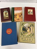 Five vintage young adult books arranged on a surface, showing covers of Robinson Crusoe, Heidi, The Secret Garden, and two other titles with cloth covers.
