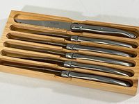 Six steak knives neatly arranged in a custom fitted wooden tray showing the set as sold.
