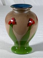 Front angled view of the vase showing the red flowers and mauve background with green stems.