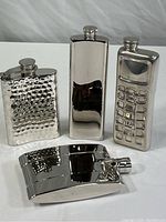 Four metal flasks arranged together showing overall shapes and finishes