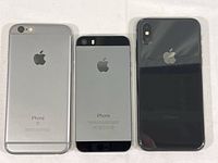 Three used iPhones placed back side up, showing Apple logos and camera arrangements - left iPhone 6S, middle iPhone 5S, right iPhone X
