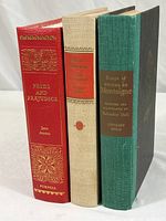 Three vintage classic hardcover books: Pride and Prejudice red leather binding, beige bound Anna Karenina, and green bound Montaigne with Salvador Dali illustrations.